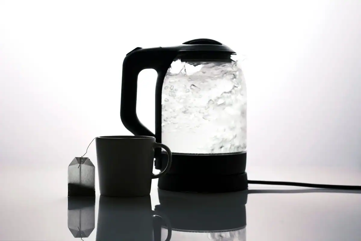 Siluetă de fierbător electric lângă o ceașcă de ceai, aparat cu consum mare de putere