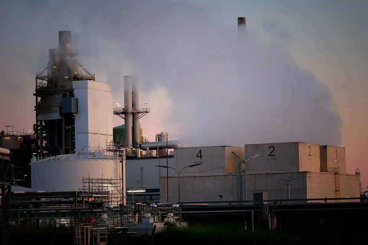 Coș de fum industrial la răsărit, cu fum pe cer, sursă de emisii pe drumul spre zero net