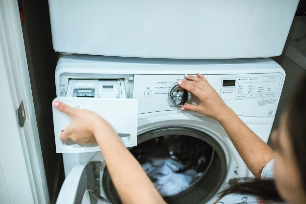 Persoană care reglează programul unei mașini de spălat rufe într-o spălătorie