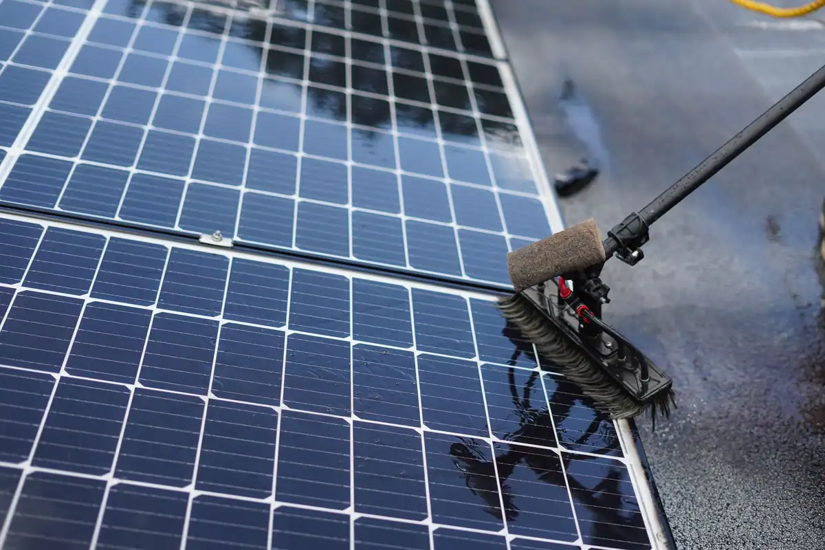 Curățarea unui panou solar cu o perie, văzută de aproape