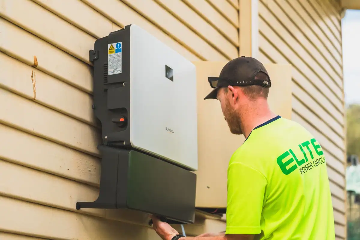 Tehnician care instalează un invertor pentru sistemul fotovoltaic în exterior