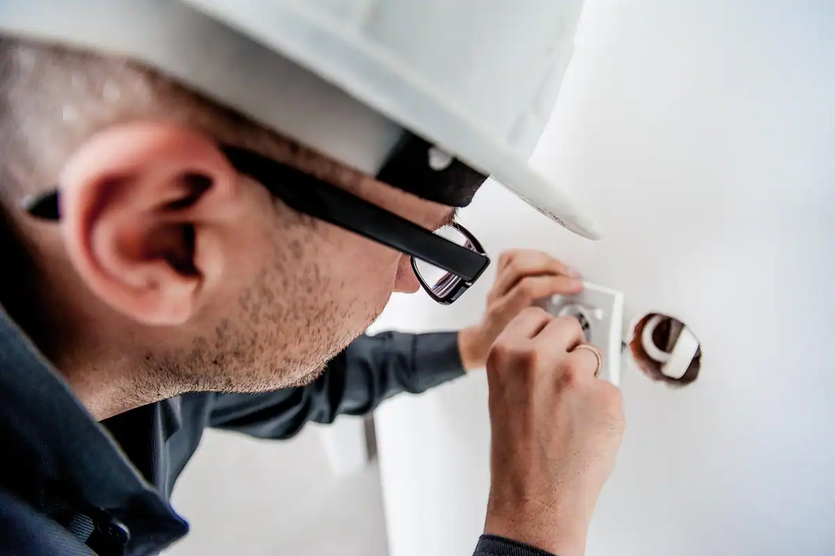 Electrician cu cască de protecție care lucrează la instalația electrică a casei