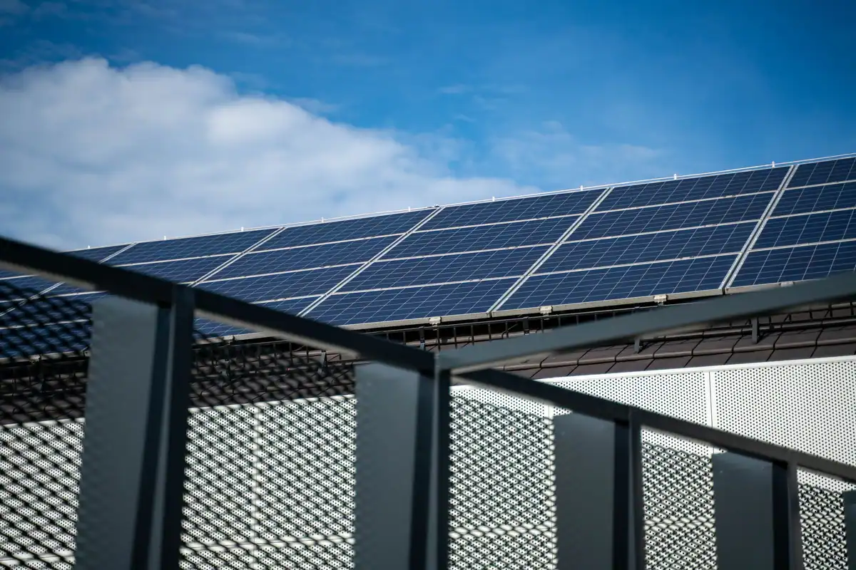 Panouri fotovoltaice moderne înclinate pe un acoperiș, văzute de aproape pe cer senin