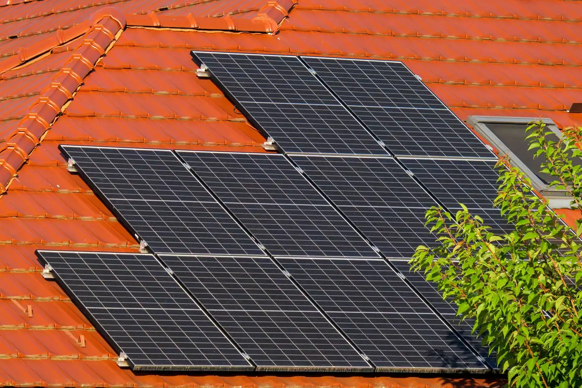 Panouri solare montate pe un acoperiș din țiglă roșie, văzute de aproape