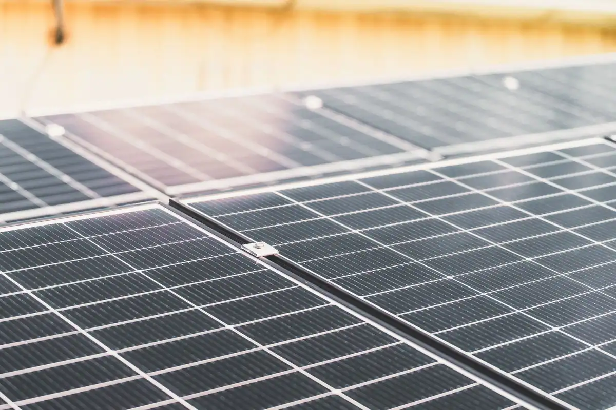 Șir de panouri solare montate pe acoperiș, luminate de soare