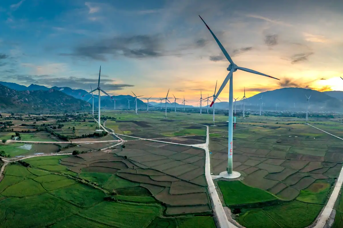 Turbine eoliene într-un peisaj verde la apus, soluție pentru energie curată