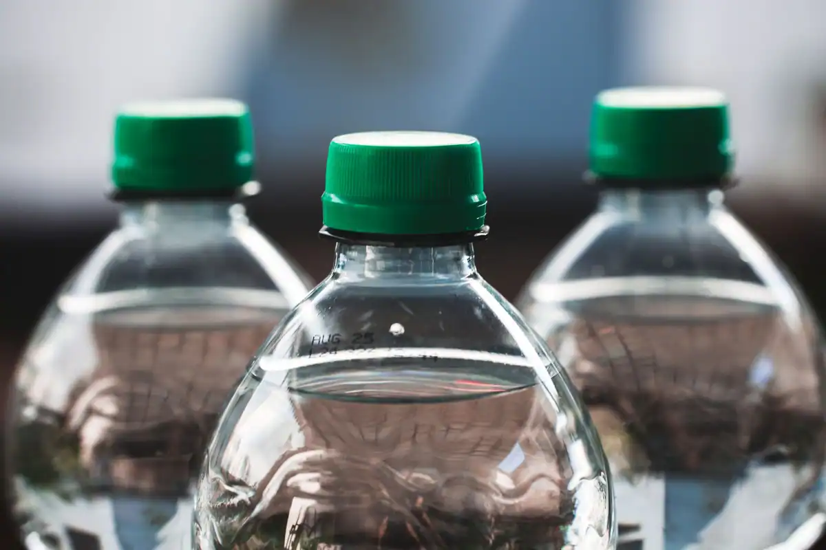 Trei sticle de plastic transparente cu capace verzi, ambalaje cu cod de reciclare