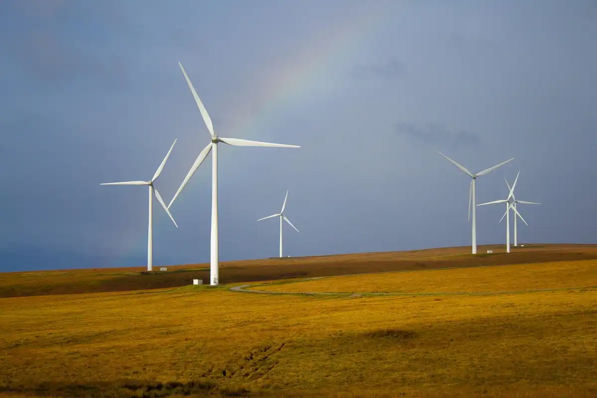Turbină eoliană mică lângă o casă de la țară, pe un câmp, pentru energie de uz casnic